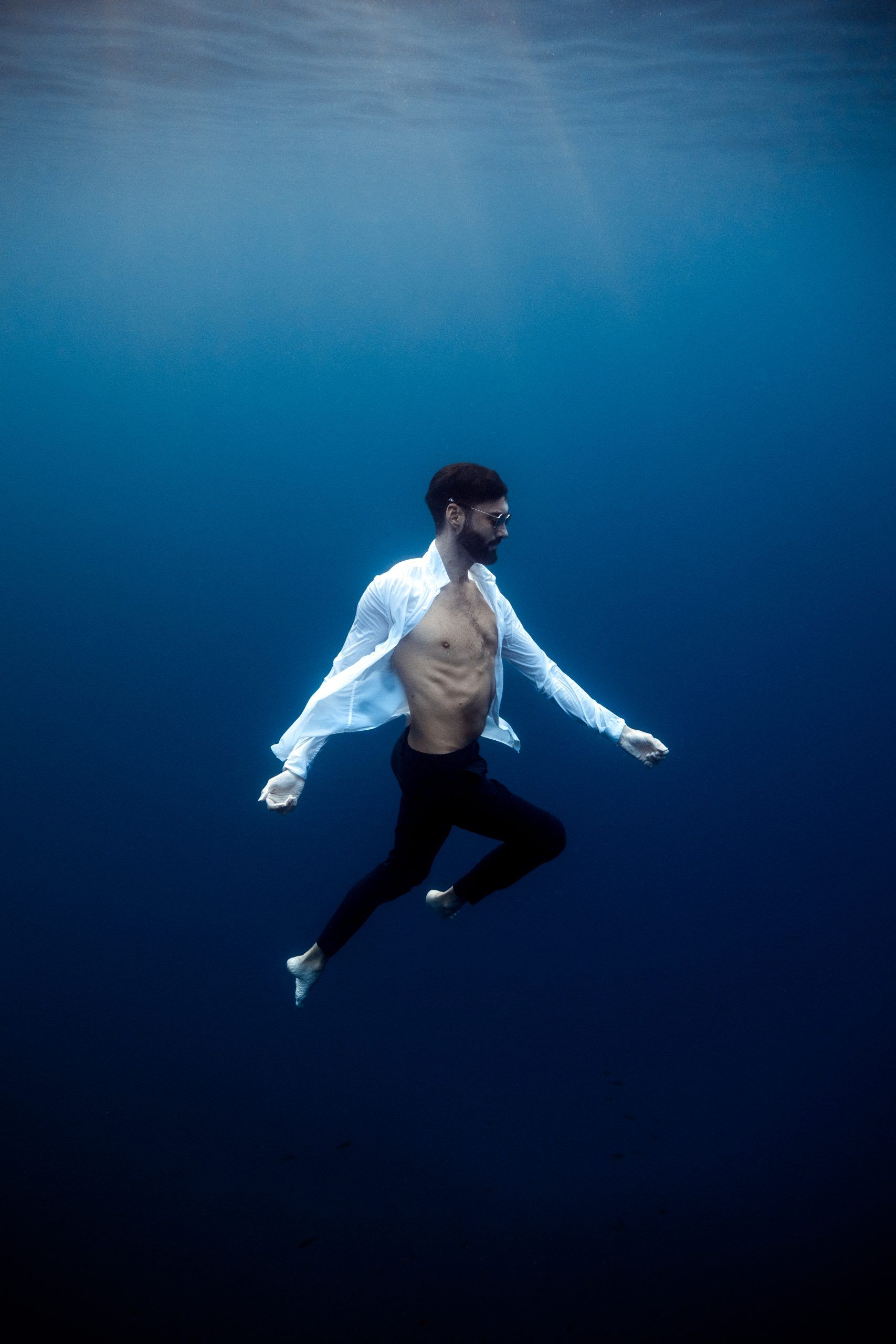 Homme suspendu dans la colonne d’eau, chemise flottante